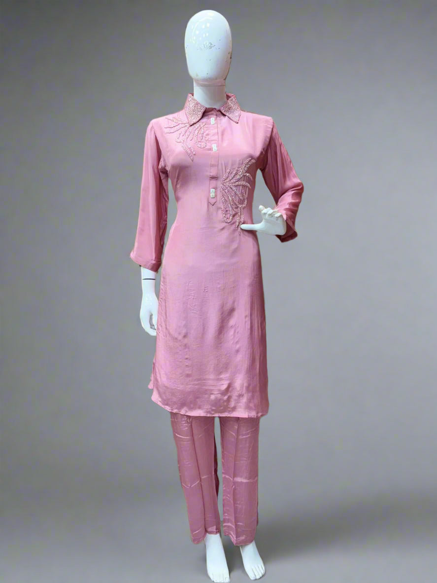 Mannequin wearing a pink outfit with a textured wall and sofa in the background