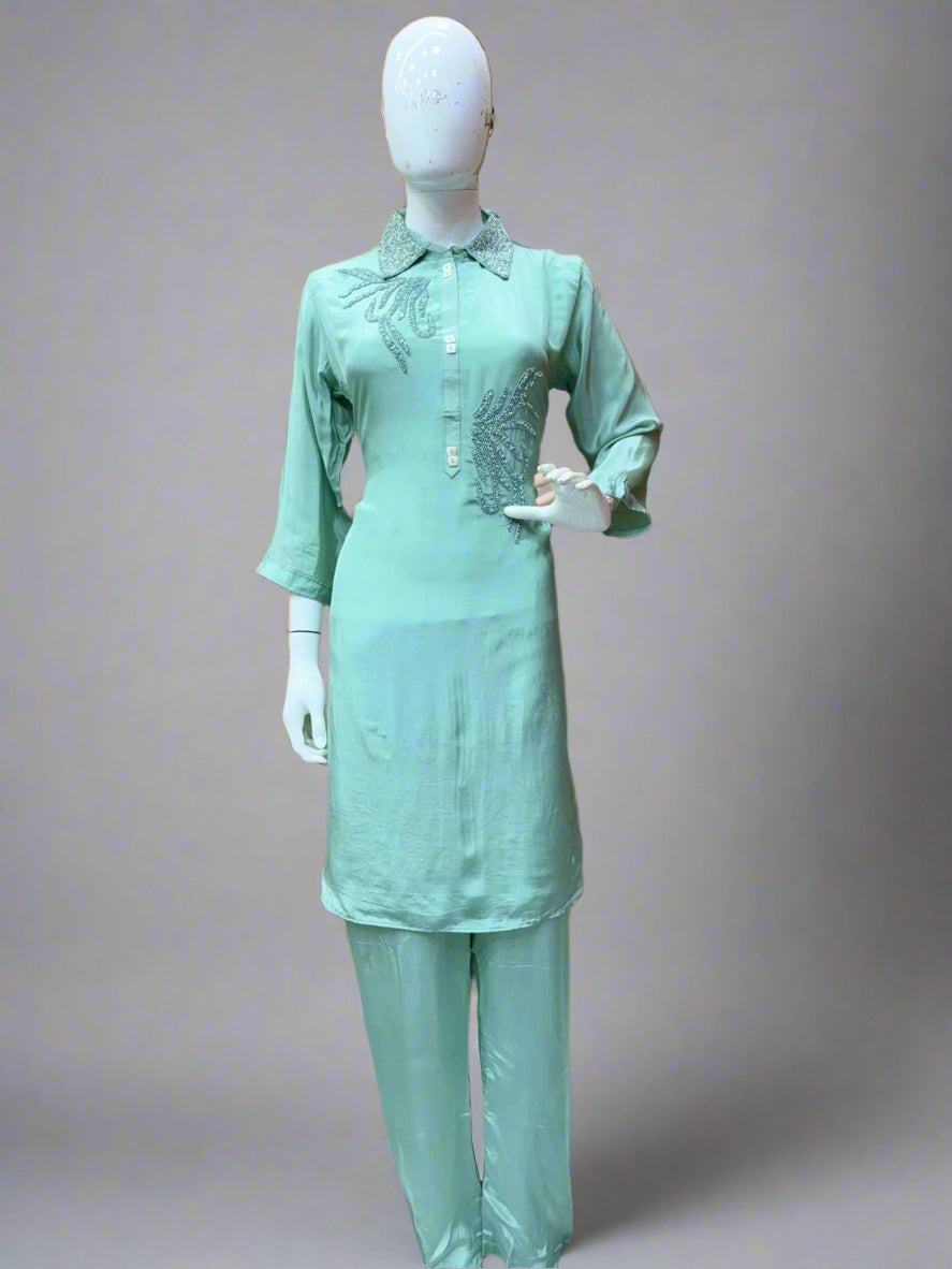 Mannequin wearing a light green outfit with embroidery in a store setting.