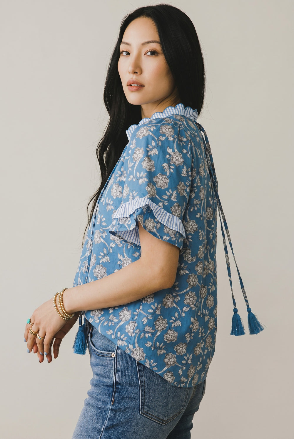 Errabelly blue floral print short sleeve blouse with striped trim, tie neck, and button detail.