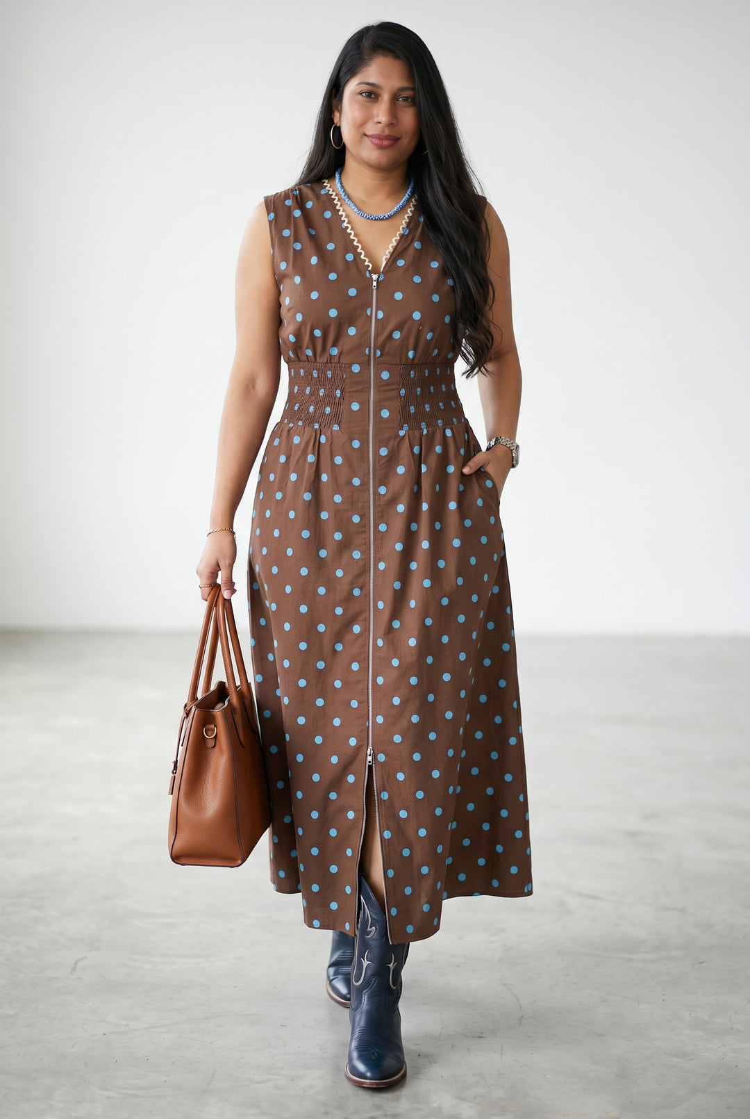 Errabelly brown sleeveless midi dress with blue polka dots, V-neck, smocked waist, and zip-up front.