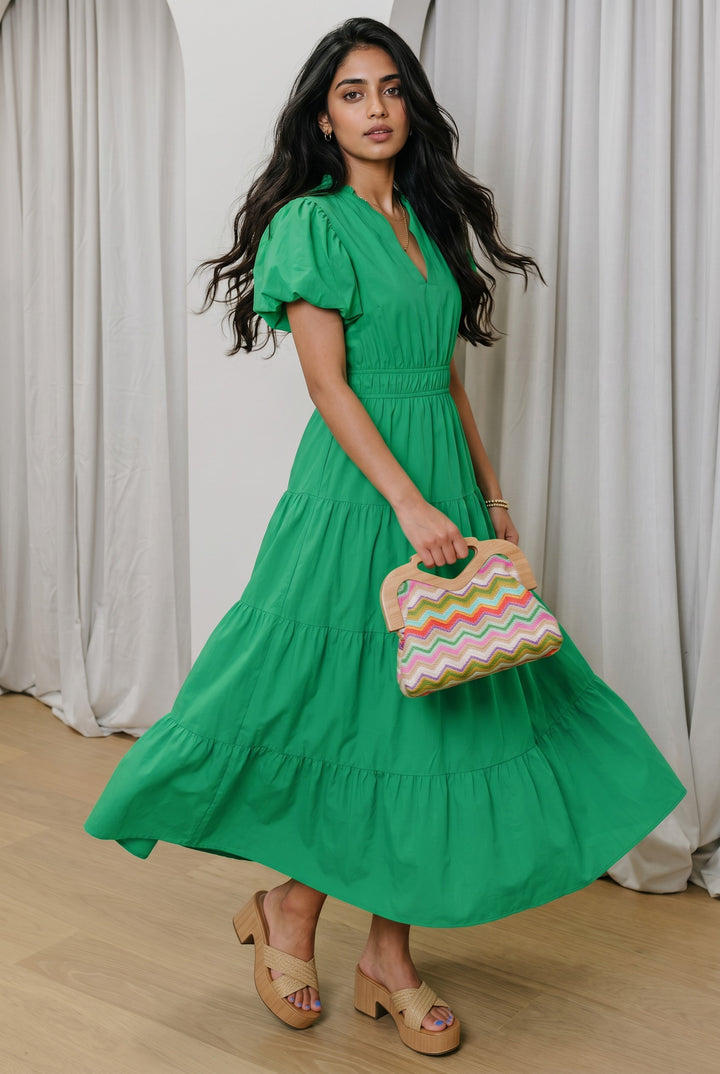Errabelly bright green V-neck maxi dress with short puff sleeves, high elasticated waist, and tiered skirt. Model is wearing platform sandals.